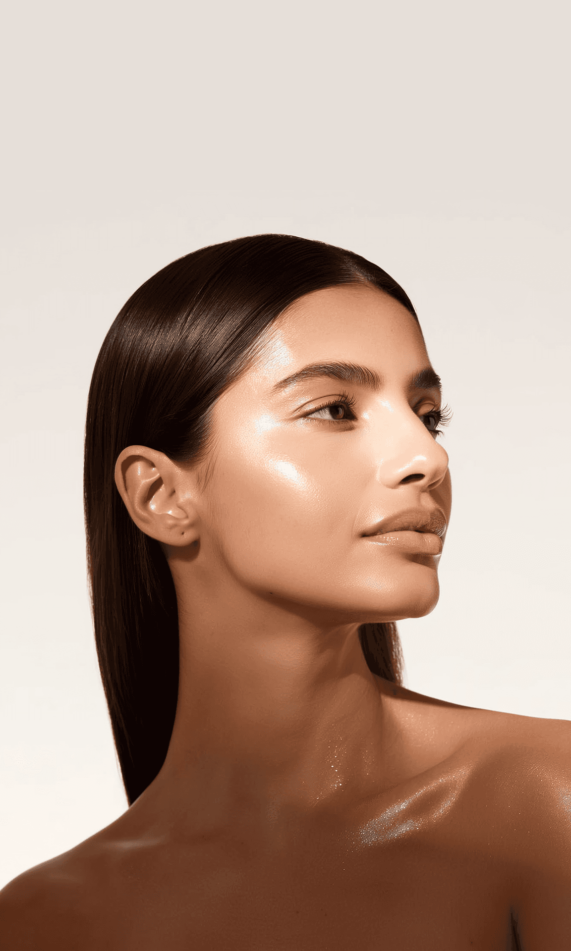 Ritratto ravvicinato di una donna con pelle luminosa, su fondo beige